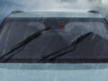 Front windshield of a car with wipers active during heavy rain.