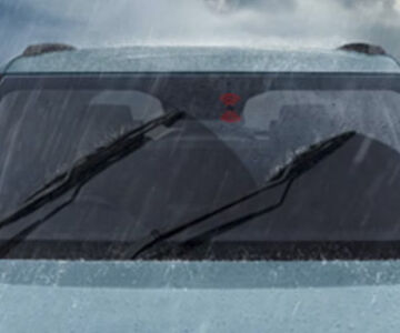 Front windshield of a car with wipers active during heavy rain.