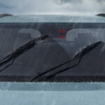 Front windshield of a car with wipers active during heavy rain.
