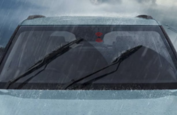 Front windshield of a car with wipers active during heavy rain.