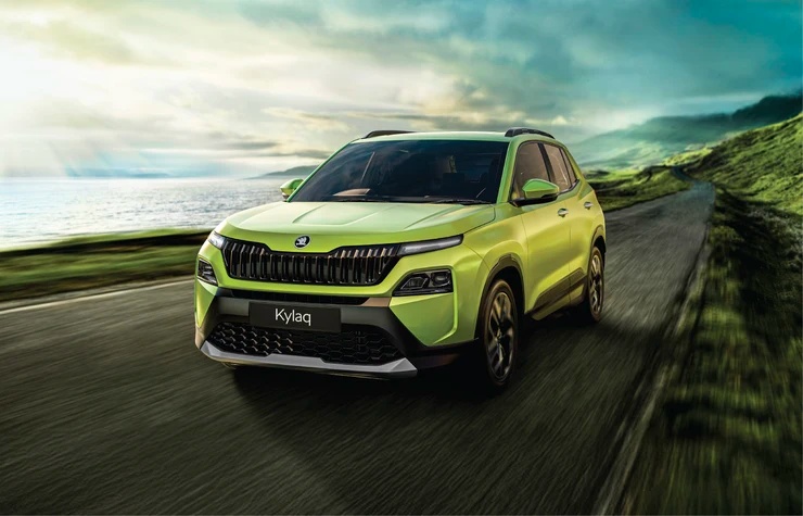 Škoda Kylaq driving on a scenic road, front view with full headlights