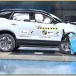 Frontal crash test of Tata Harrier EV with dummies and deployed airbags visible.