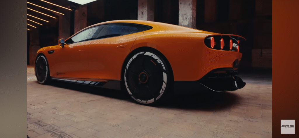 Rear view of an orange Mercedes AMG concept car with futuristic tail lights and sporty design in a dimly lit urban setting.