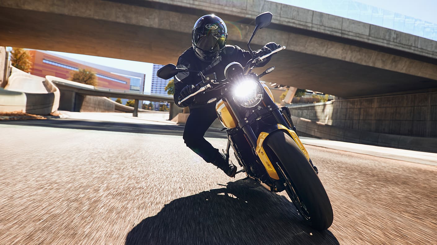 Rider on the Triumph Trident 660 enjoying a relaxed cruise through open highways, illustrating its upright ergonomics and new cruise control feature