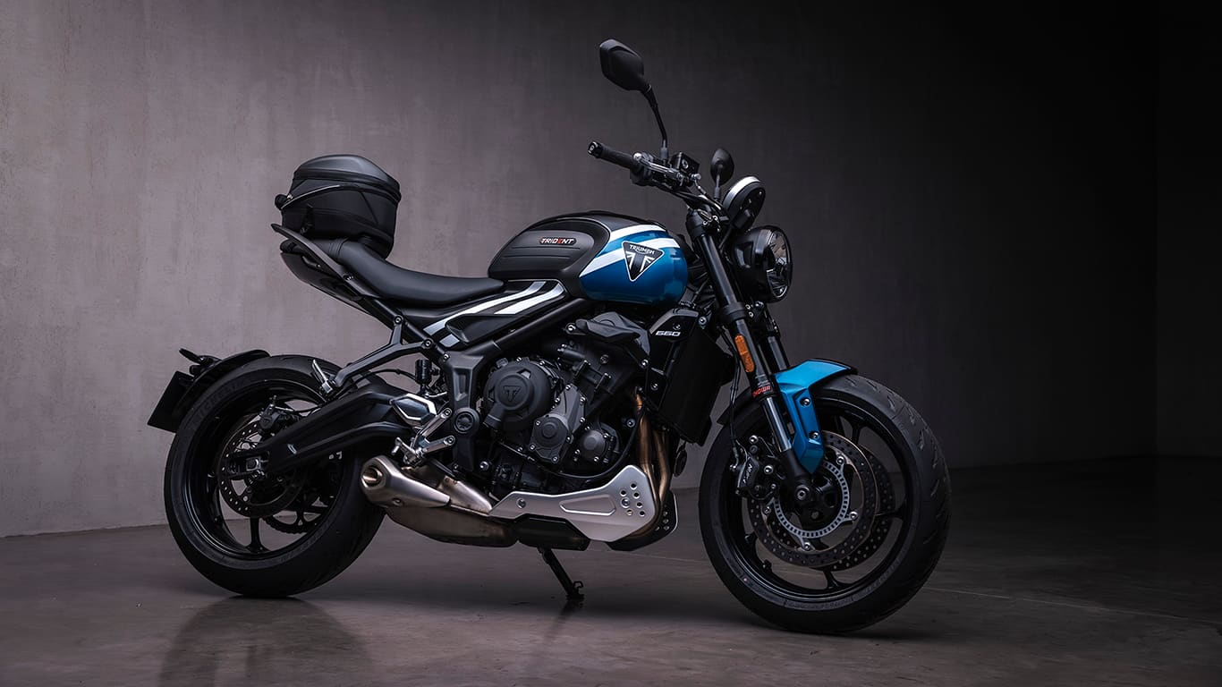 2025 Triumph Trident 660 with factory accessories including flyscreen, bar-end mirrors, and belly pan in an urban night-time setting